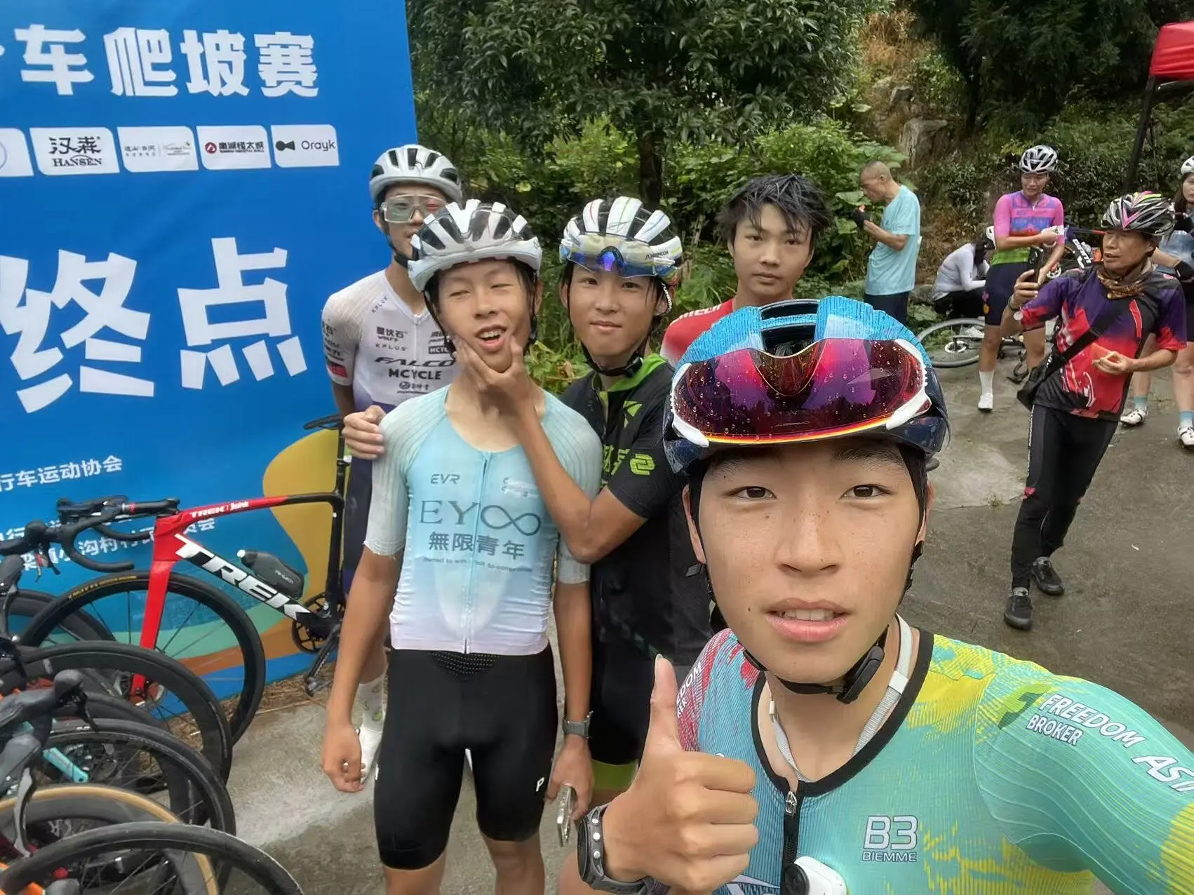 几名车手在写有“终点”的背景板前自拍合影